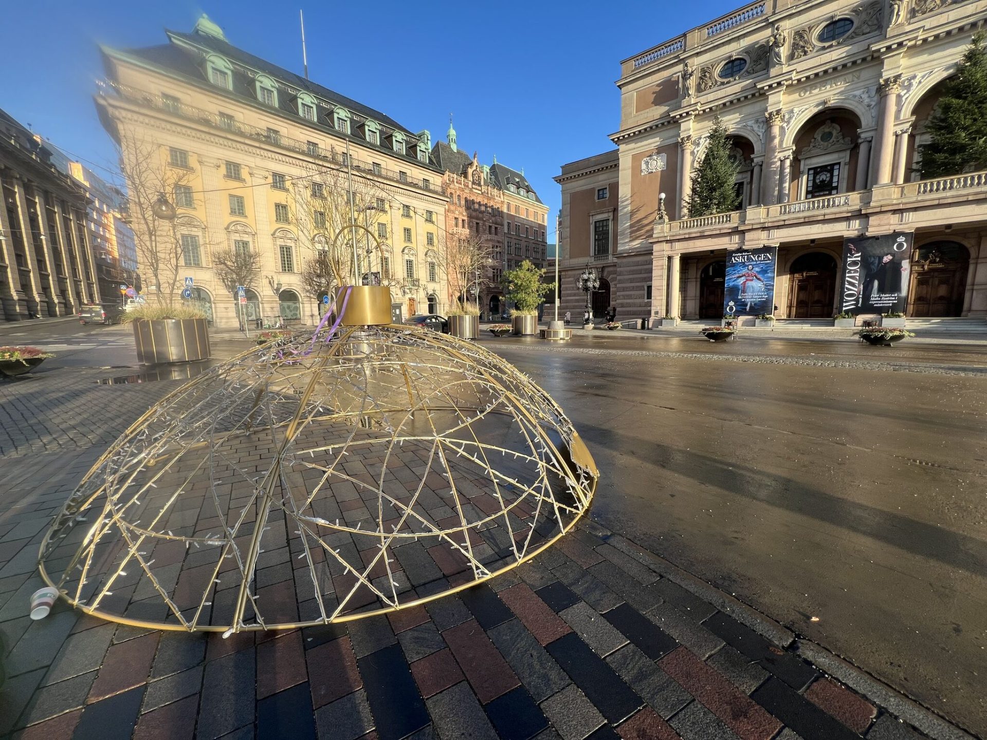 En halv julkula som håller på att monteras på ett torg.